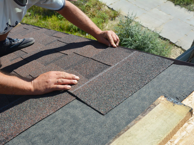 worker installing some roofing asphalt tiles